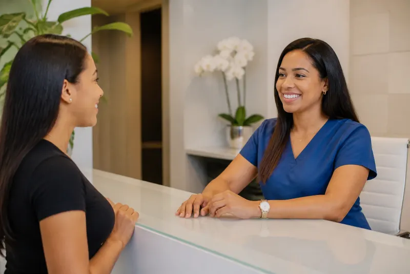 Recepcionista de una clínica recibiendo con una sonrisa a un paciente
